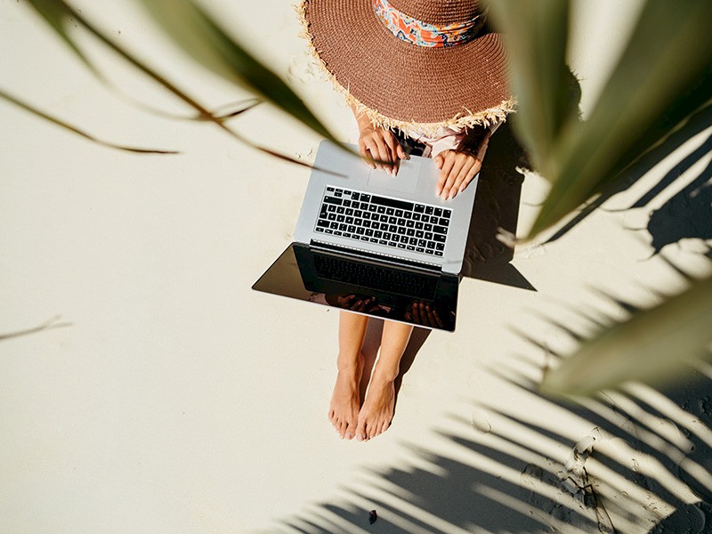 Woman working remotely on her laptop at the beach
